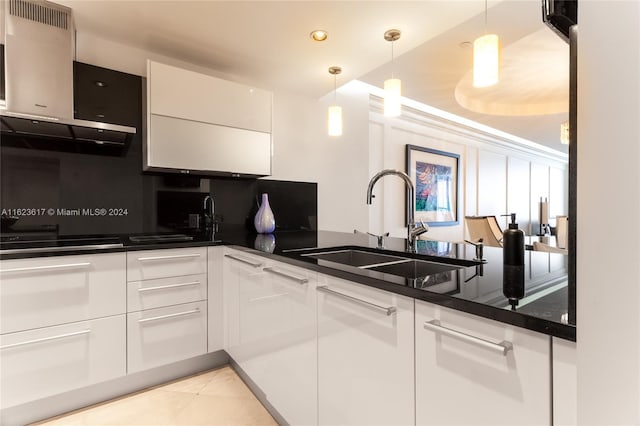 kitchen featuring sink, white cabinetry, light tile patterned floors, and wall chimney range hood