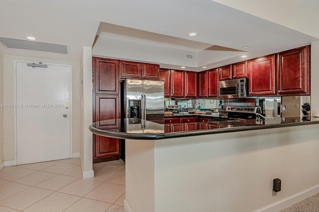 kitchen with appliances with stainless steel finishes, light tile patterned floors, and kitchen peninsula