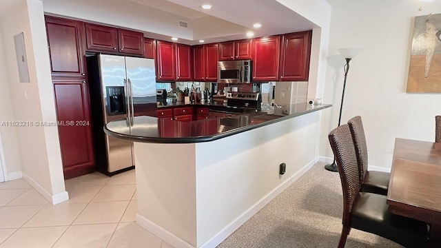 kitchen with light tile patterned flooring, appliances with stainless steel finishes, and kitchen peninsula