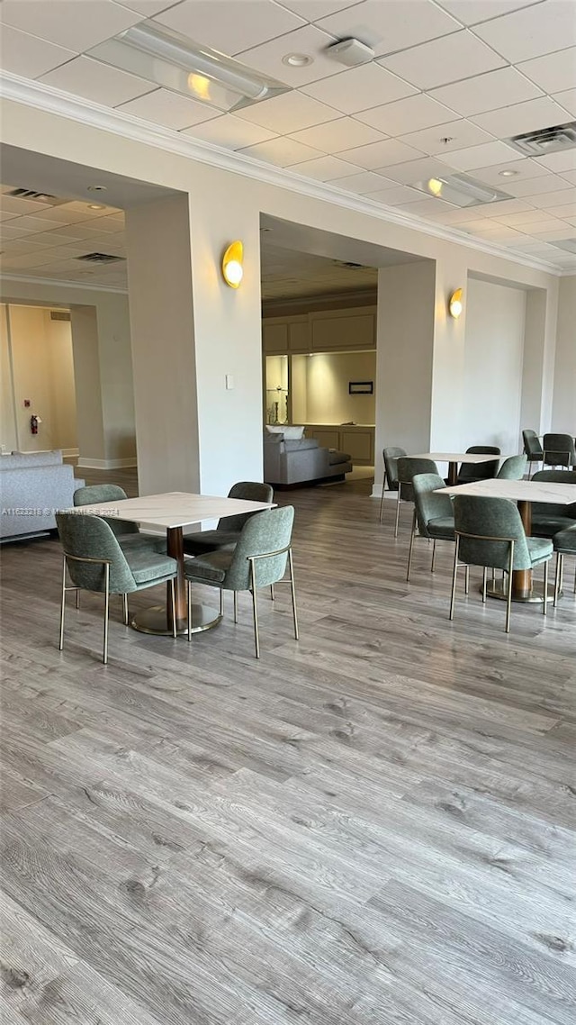 dining space with hardwood / wood-style flooring, ornamental molding, and a paneled ceiling