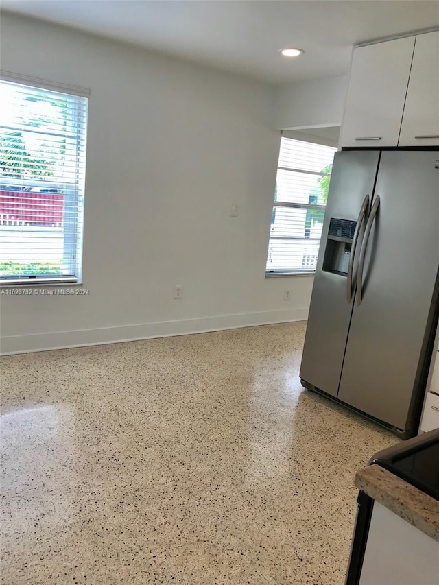 kitchen with stainless steel refrigerator with ice dispenser, white cabinetry, and a wealth of natural light