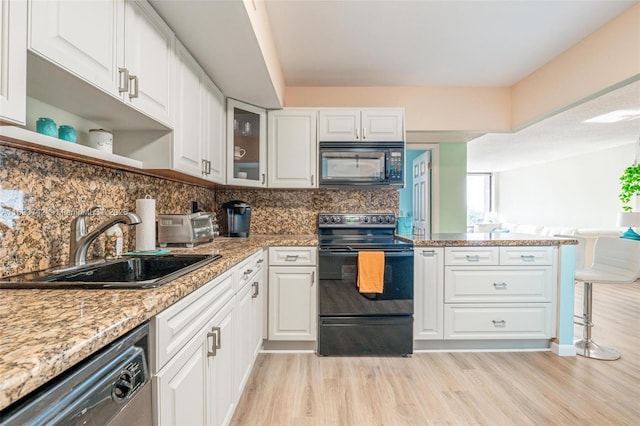 kitchen with light stone countertops, white cabinetry, sink, decorative backsplash, and black appliances