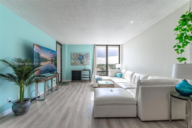 living room featuring floor to ceiling windows, light hardwood / wood-style flooring, and a textured ceiling