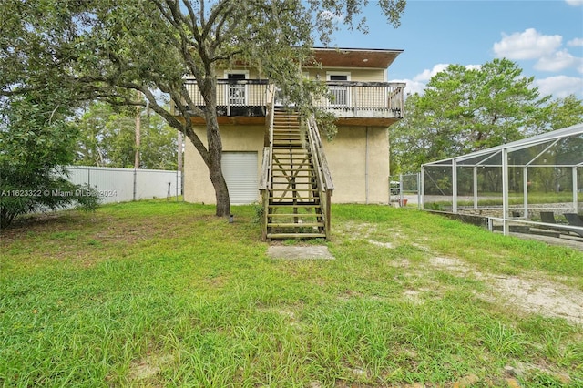 back of property featuring a deck, a lanai, and a yard