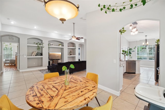 dining room featuring ceiling fan with notable chandelier, built in features, and light tile patterned floors