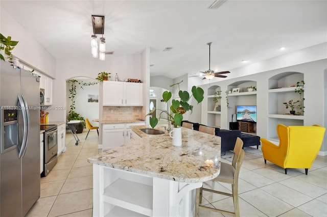 kitchen featuring built in features, appliances with stainless steel finishes, decorative light fixtures, an island with sink, and white cabinets