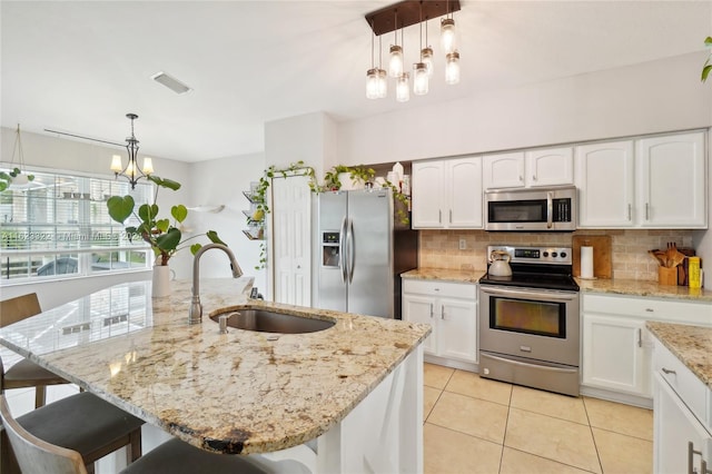 kitchen featuring hanging light fixtures, sink, an island with sink, and stainless steel appliances