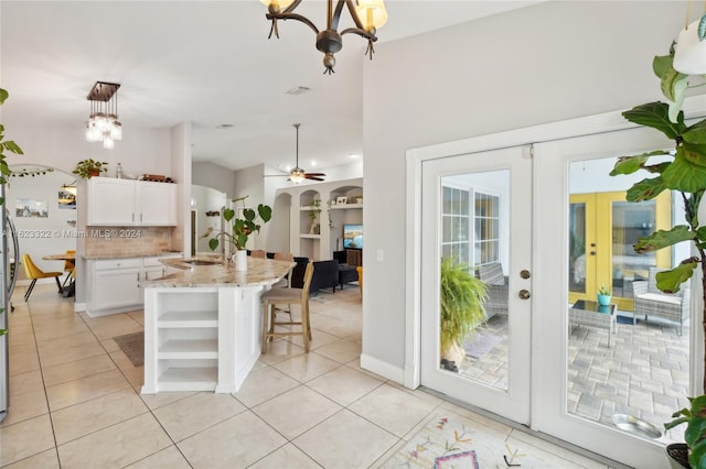 kitchen with white cabinets, ceiling fan with notable chandelier, a kitchen island with sink, and hanging light fixtures