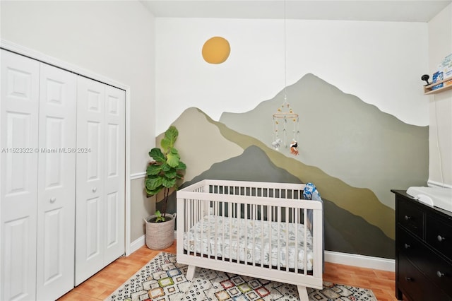 bedroom with a closet, light wood-type flooring, and a crib