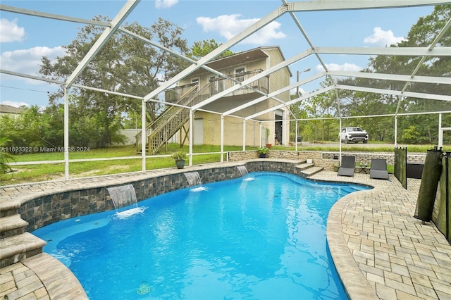 view of pool with glass enclosure, a patio, and pool water feature