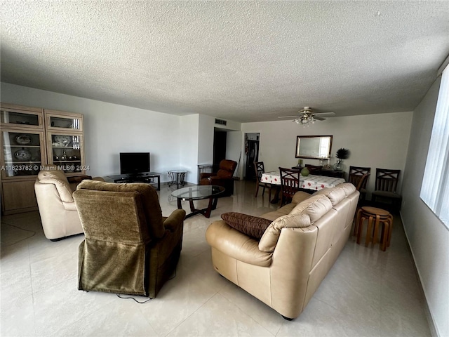 living room with ceiling fan and a textured ceiling