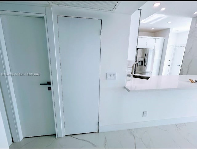 kitchen with sink, stainless steel fridge, and white cabinets