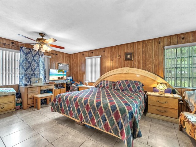 bedroom featuring ceiling fan, wooden walls, and light tile patterned floors