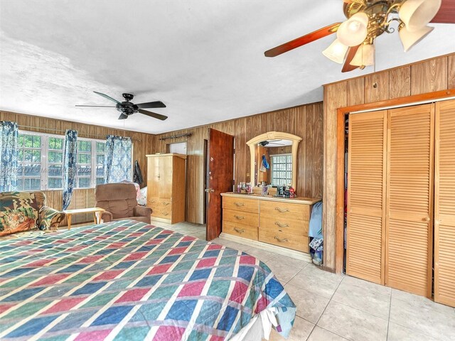 bedroom with wood walls, a closet, ceiling fan, and tile patterned floors