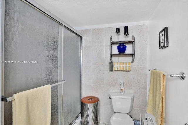 bathroom with toilet, a shower with door, and tile walls