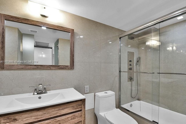 full bathroom featuring tile walls, combined bath / shower with glass door, vanity, and toilet