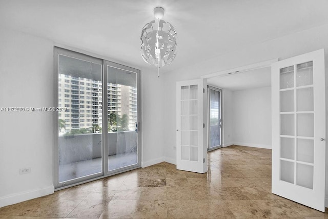 spare room featuring french doors and an inviting chandelier