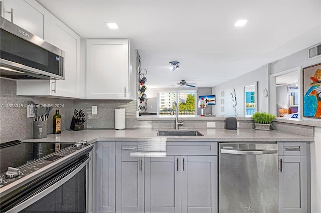 kitchen with sink, gray cabinets, white cabinetry, stainless steel appliances, and decorative backsplash