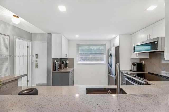 kitchen featuring light stone countertops, appliances with stainless steel finishes, and white cabinets