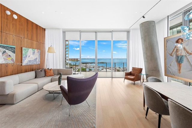 living room with floor to ceiling windows, plenty of natural light, wooden walls, and a water view