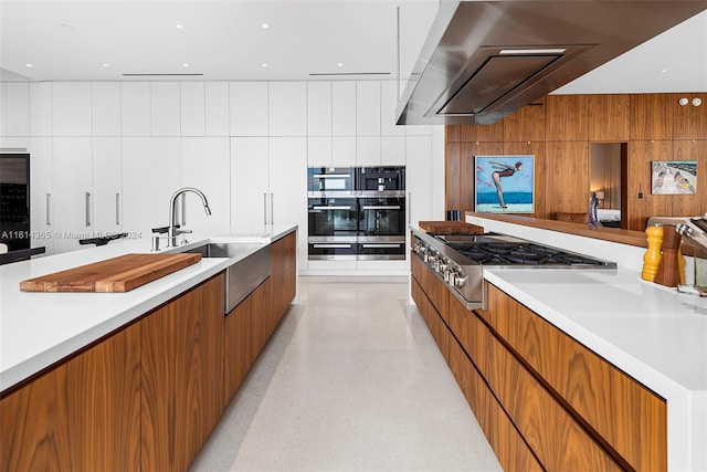 kitchen with sink, stainless steel gas stovetop, wall chimney range hood, and wooden walls