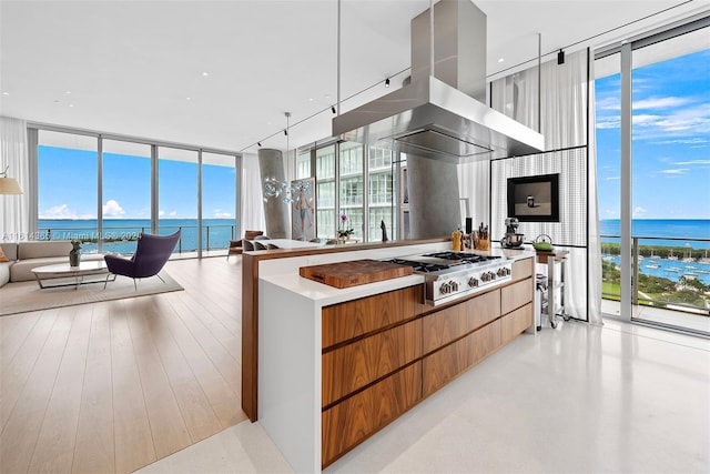 kitchen featuring floor to ceiling windows, stainless steel gas stovetop, island exhaust hood, and a water view