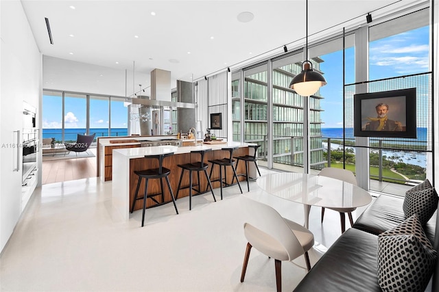 kitchen with decorative light fixtures, expansive windows, a kitchen breakfast bar, and a water view