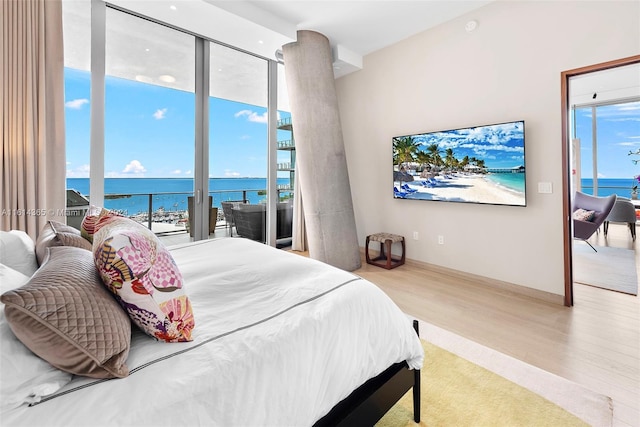 bedroom featuring access to outside, expansive windows, and light hardwood / wood-style flooring