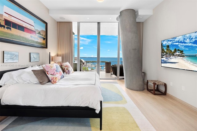 bedroom with light hardwood / wood-style floors, access to outside, and expansive windows