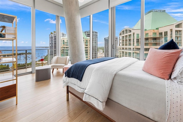 bedroom featuring a wall of windows, a water view, and wood-type flooring