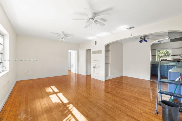 1310 15th St, Miami Beach, FL 33139 - unfurnished living room featuring ceiling fan, arched walkways, light wood-style flooring, and baseboards