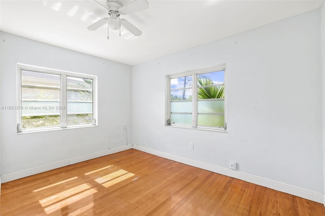 empty room with ceiling fan, hardwood / wood-style flooring, and a wealth of natural light