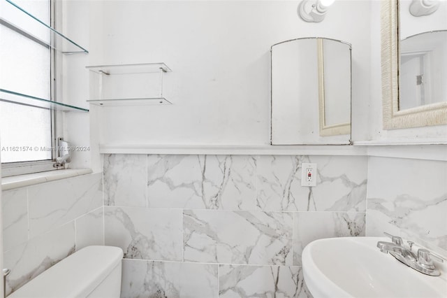 bathroom featuring sink, tile walls, and toilet