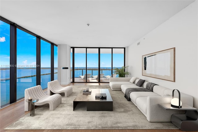 living room with a wall of windows, a water view, and hardwood / wood-style floors