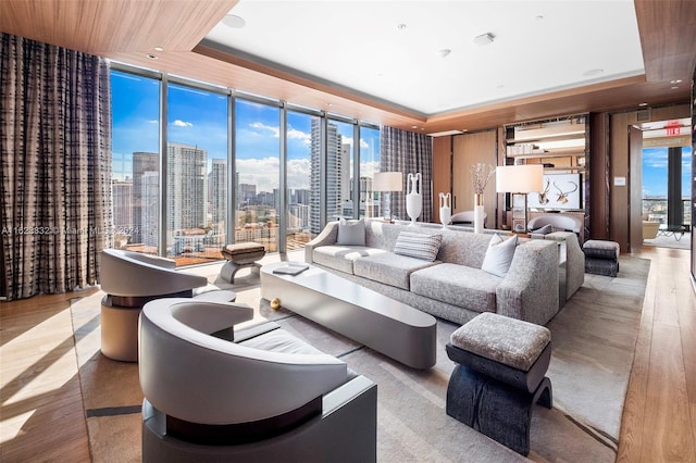 living room featuring a raised ceiling, floor to ceiling windows, and light hardwood / wood-style floors