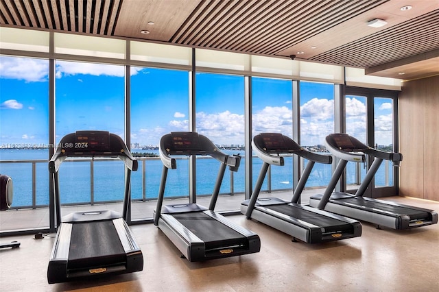 workout area featuring floor to ceiling windows, a water view, and wood ceiling