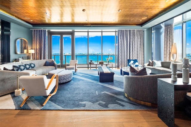 living room featuring wood ceiling, a wall of windows, hardwood / wood-style floors, a water view, and a raised ceiling