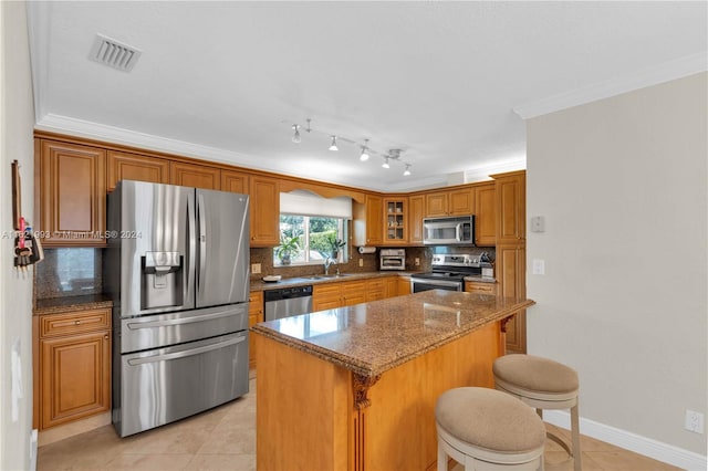 kitchen with appliances with stainless steel finishes, a breakfast bar, sink, backsplash, and a kitchen island