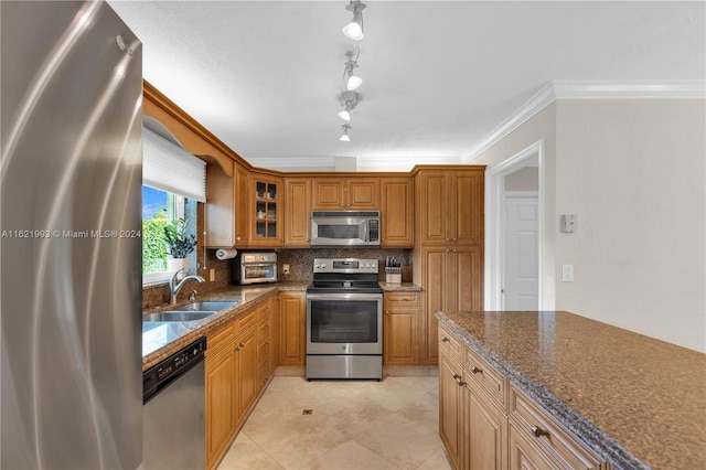 kitchen with rail lighting, ornamental molding, sink, appliances with stainless steel finishes, and light tile patterned floors