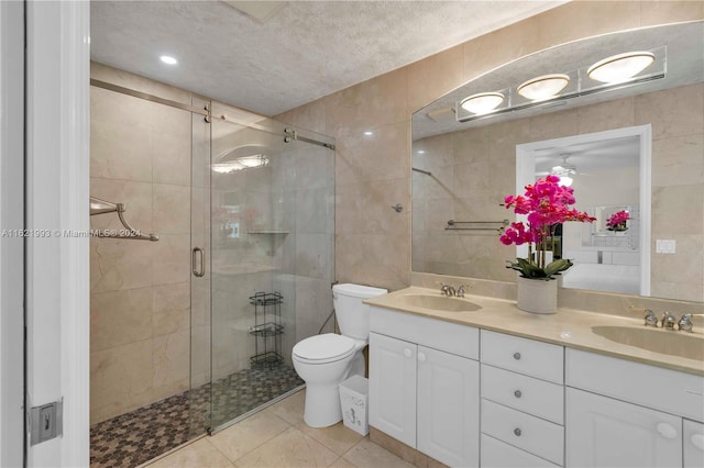 bathroom with tile patterned floors, walk in shower, tile walls, double vanity, and toilet