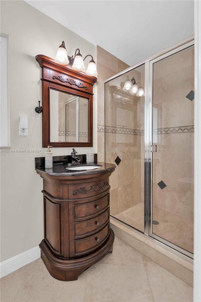 bathroom featuring a shower with shower door, vanity, and tile patterned flooring