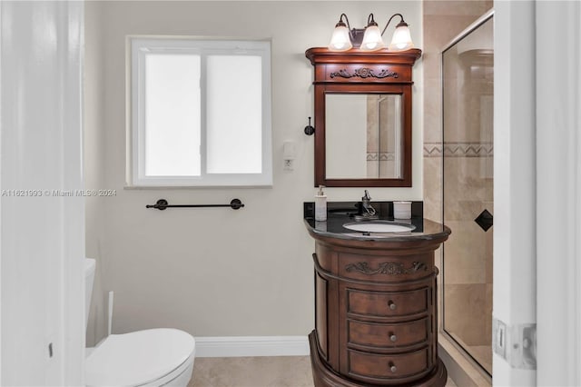 bathroom featuring tile patterned flooring, a shower with shower door, toilet, and vanity