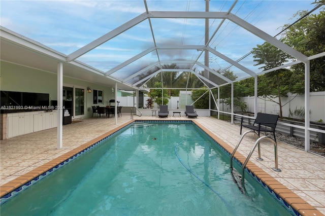 view of swimming pool featuring a patio area and a lanai