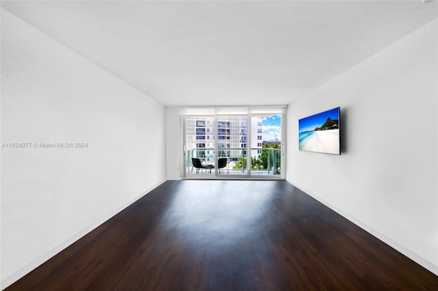 empty room with a wall of windows and hardwood / wood-style flooring