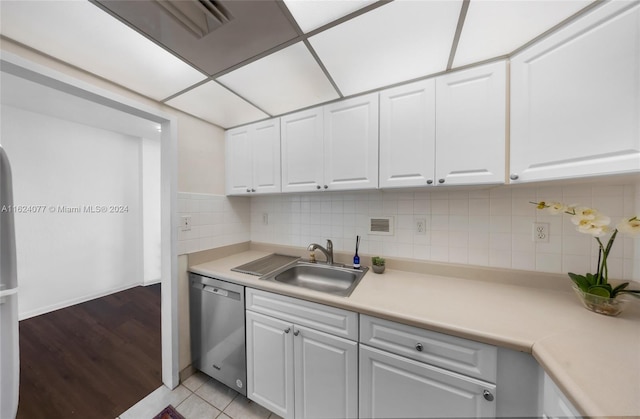 kitchen featuring light tile patterned flooring, tasteful backsplash, white cabinets, sink, and dishwasher