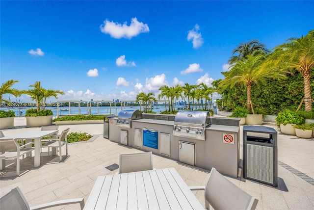 view of patio featuring a water view, an outdoor kitchen, and a grill