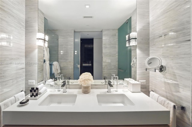 bathroom featuring dual bowl vanity and tile walls