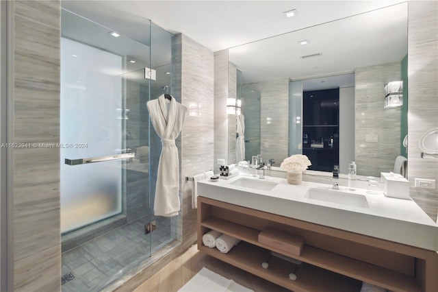 bathroom featuring dual vanity, a shower with door, tile walls, and tile patterned floors