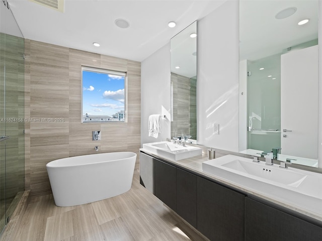 bathroom with tile walls, vanity, and independent shower and bath