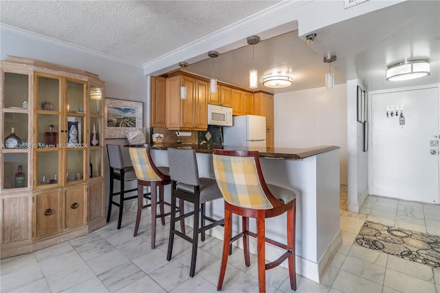 kitchen with hanging light fixtures, light tile patterned flooring, kitchen peninsula, and white appliances